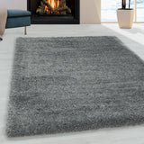 Grijze hoogpolig fluffy shaggy vloerkleed voor een openhaard in de woonkamer